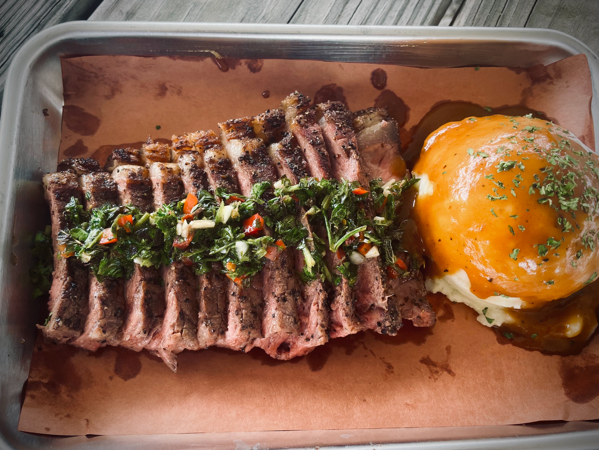 Sliced ribeye with chimichurri and loaded potato